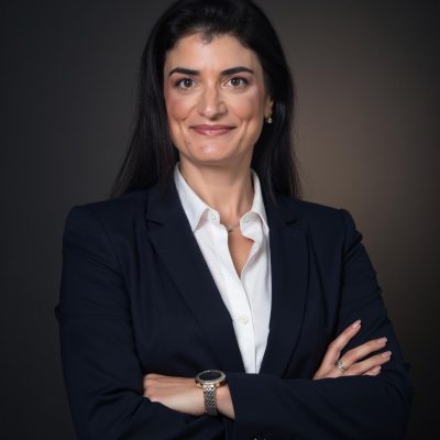 דיוקן עורכת הדין בחליפה כהה ובחולצה לבנה על רקע כהה